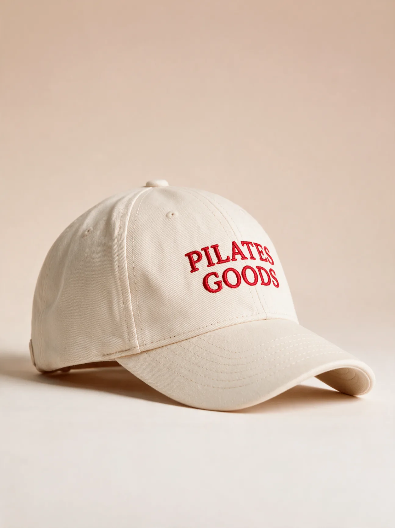Custom branded cream dad cap with red embroidered Pilates Goods logo, Pantone-matched to your studio brand
