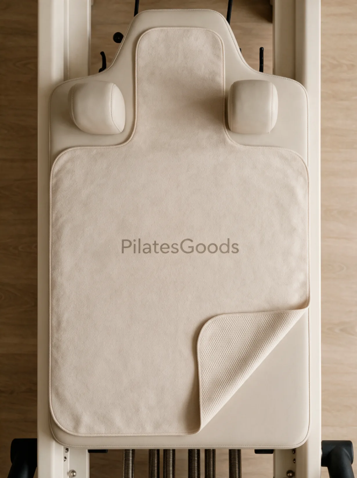 Custom branded reformer grip towels in navy, pink, beige and teal with Pilates Goods logo on Pilates reformer equipment
