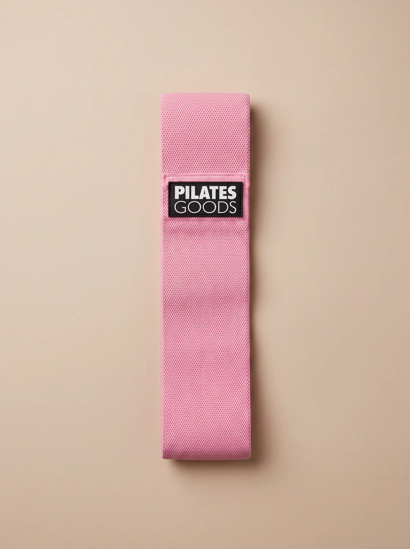 Custom branded pink resistance band with woven PilatesGoods polyester logo tag
