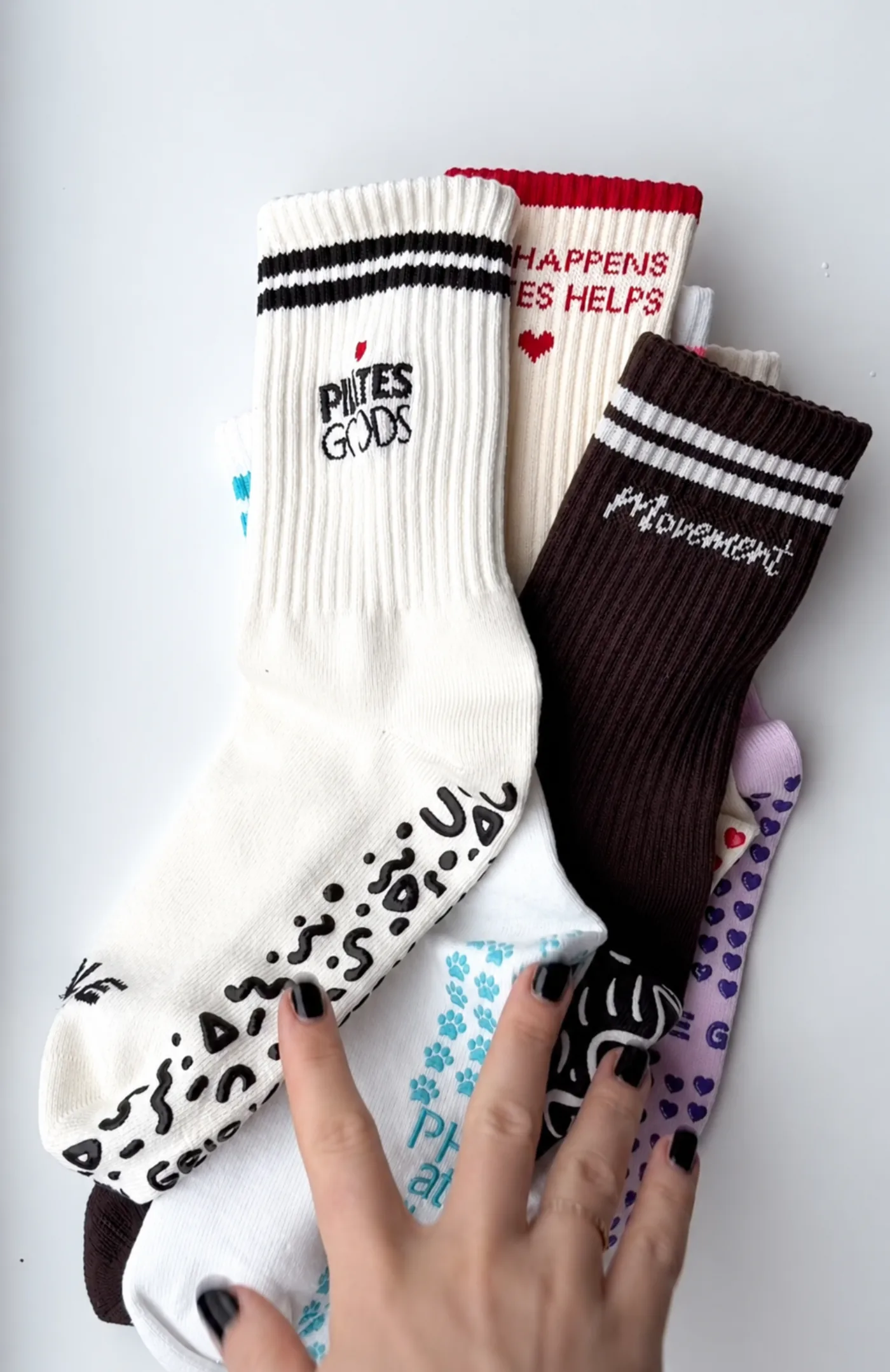 Custom branded Pilates grip socks collection with embroidered studio logos and silicone heart, dot and pattern grip soles in ivory, brown and lilac